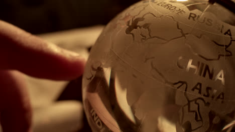 person pointing at a glass globe