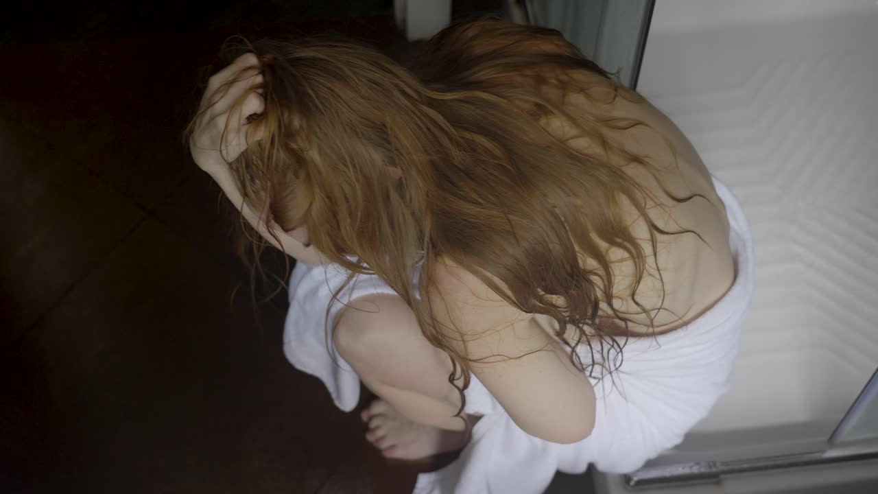 Beautiful woman sitting in her shower crying
