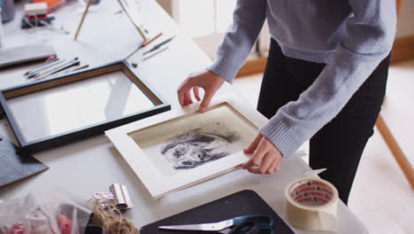 close up of female teenage artist framing picture in studio