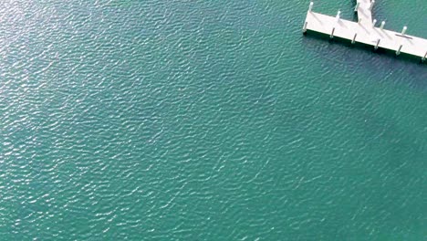 Turquoise-wavy-water-with-a-white-dock-beach-and-mansions-in-Martha's-Vineyard