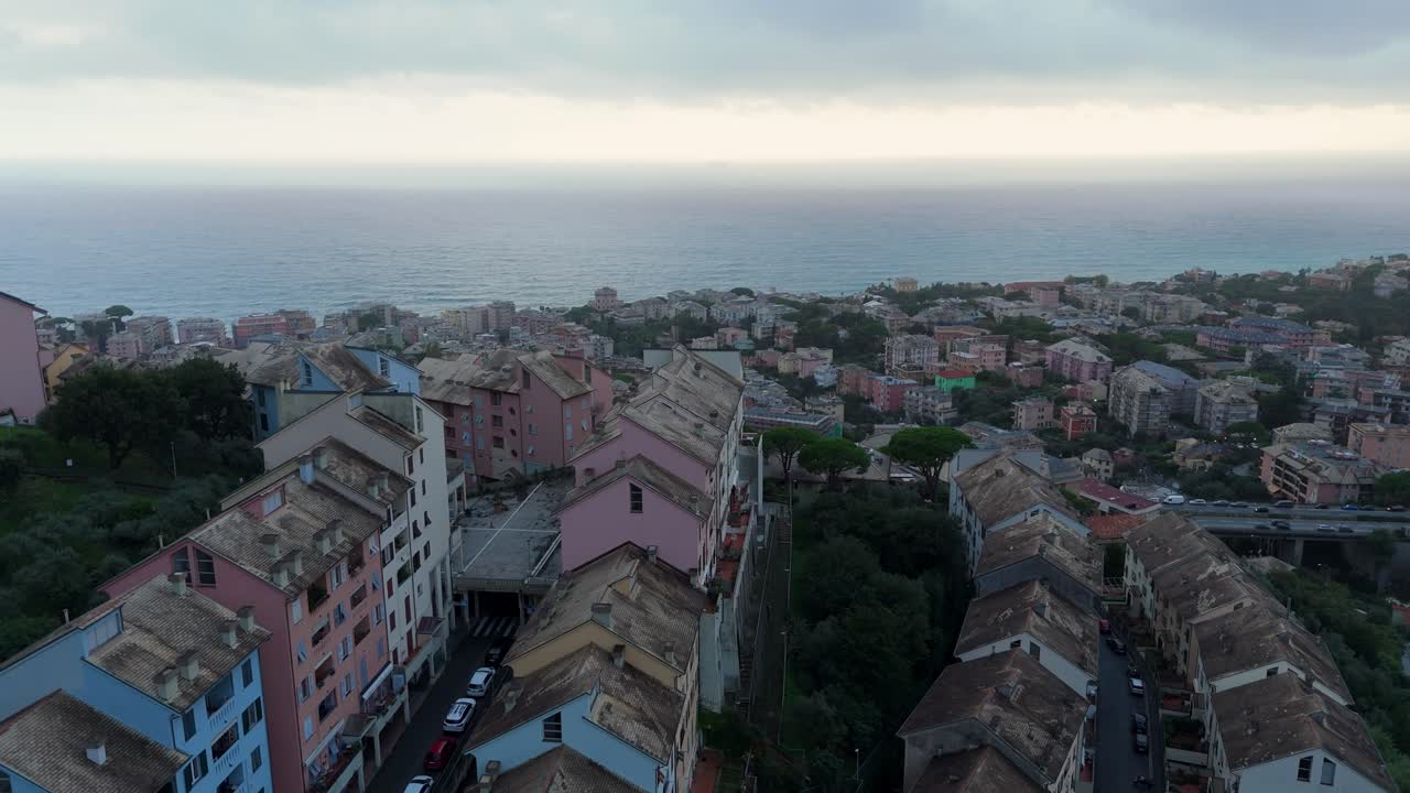 Pastel-colored buildings on a coastal town in italy under a cloudy sky, aerial view