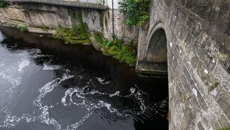 water flows under a historic stone bridge