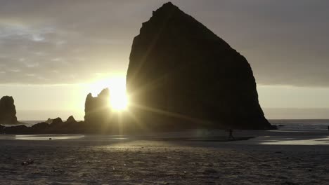 Hermoso-Atardecer-En-Haystack-Rock,-Cannon-Beach-Oregon,-Persona-Corriendo-En-La-Playa