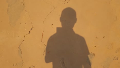 Shadow-of-man-holding-gimbal-in-one-hand-reflected-on-yellow-wall