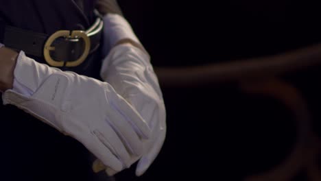 Cinematic-close-up-shot-of-a-woman-putting-on-white-horse-riding-gloves-and-preparing-herself-for-a-horse-ride-in-Slow-Motion,-Slomo