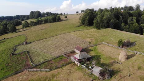 Lonely-house-in-the-middle-of-a-meadow-up-in-the-Carpathian-mountains,-aerial-footage