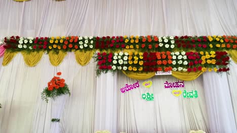 toma de drone de un escenario de boda indio decorado con sillas y flores coloridas.