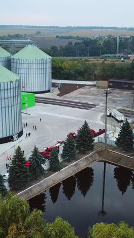 flying above the modern elevator plant territory. car park, artificial pond and railways locating at the industrial zone. vertical video