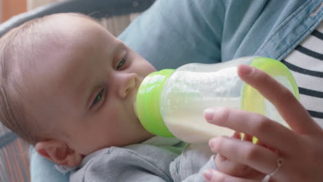 happy mother feeding baby drinking from milk bottle loving mom caring for infant enjoying motherhood relaxing at home