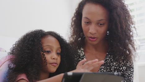 Madre-Con-Hija-Sentada-En-El-Suelo-En-El-Dormitorio-Del-Niño-Usando-Una-Tableta-Digital-Juntos