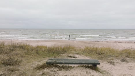 Aufnahme-Einer-Luftaufnahme-Der-Ostseeküste-An-Einem-Bewölkten-Tag,-Bilderrahmen,-Alter-Holzsteg,-Weißer-Sandstrand,-Große-Sturmwellen,-Die-Gegen-Die-Küste-Schlagen,-Drohnenaufnahme,-Die-Sich-Vorwärts-Bewegt