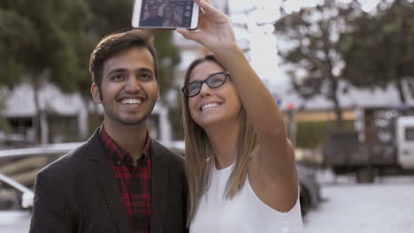 una alegre pareja multiétnica tomando una selfie en la calle
