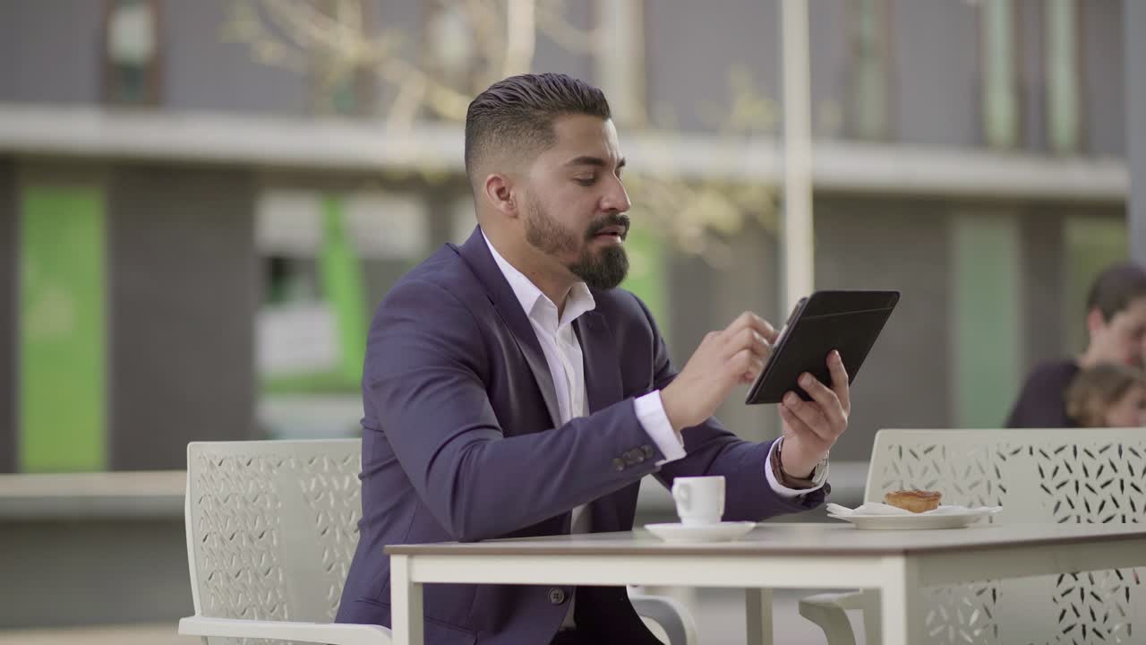 hombre de negocios serio hablando y usando una tableta en un café