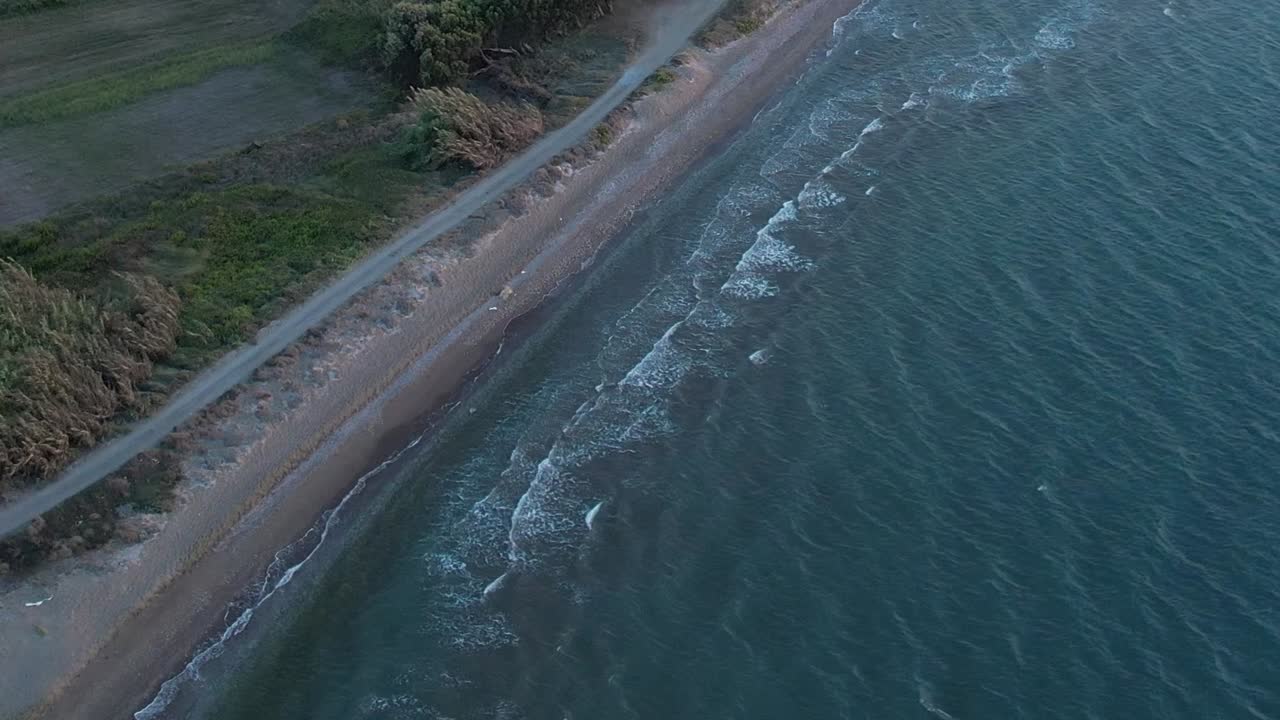 Calm waves kiss the shoreline in aerial view of Greece's coast