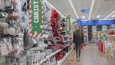 shop displaying christmas tree decorations as young teenager browses