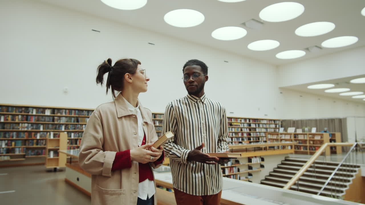 Multiethnic Man and Woman Walking in Library and Talking