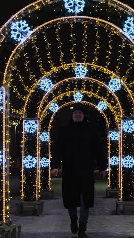 person walking under a wintery archway decorated with christmas lights