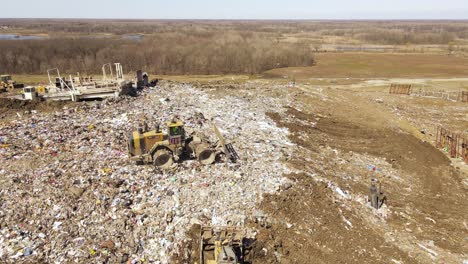 Landfill-with-flying-birds-and-industrial-equipment-working,-aerial-view