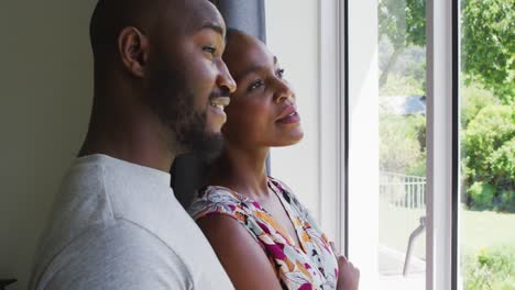 Pareja-Afroamericana-Hablando-Entre-Sí-Mientras-Miran-Por-La-Ventana-En-Casa