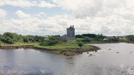 aerial reverse shot over water of dunguaire castle in county galway, ireland