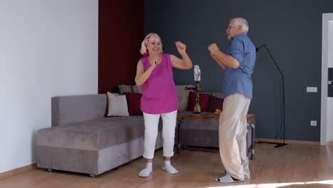 Senior-mature-couple-dancing-together-in-room-at-home-during-quarantine-lockdown-for-coronavirus