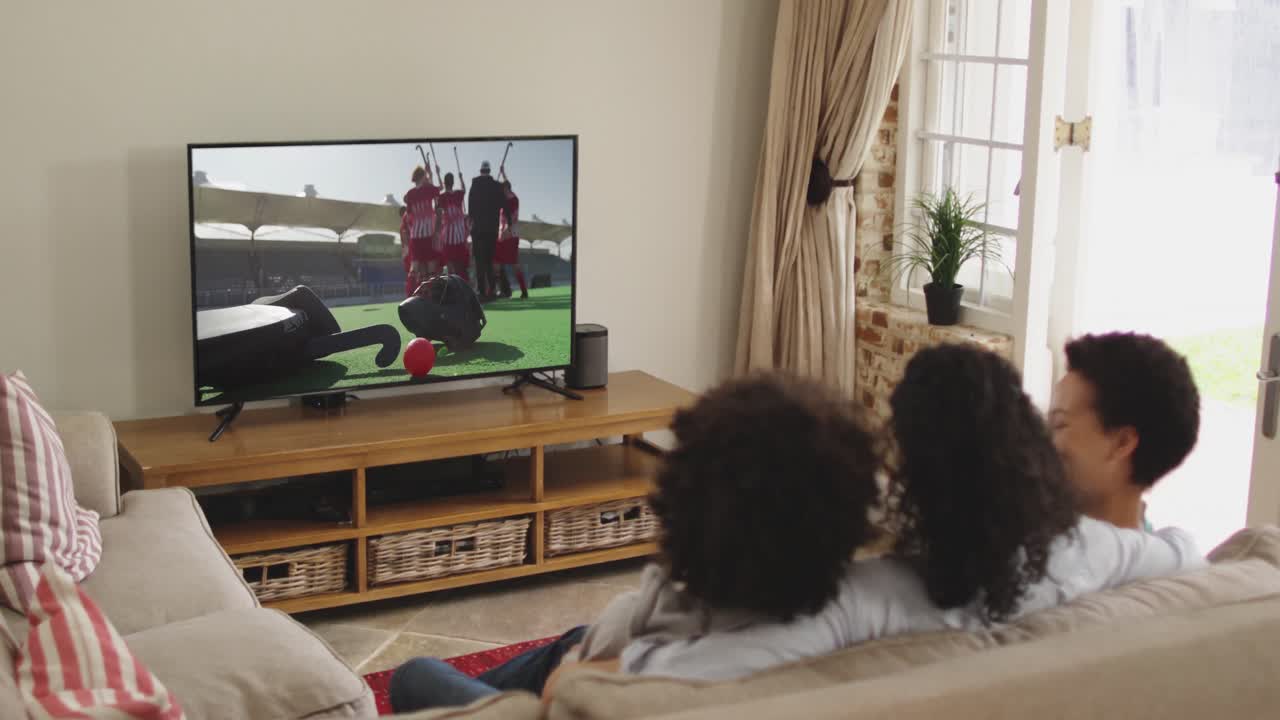 Famiglia felice seduta a casa insieme che guarda una partita di hockey in TV