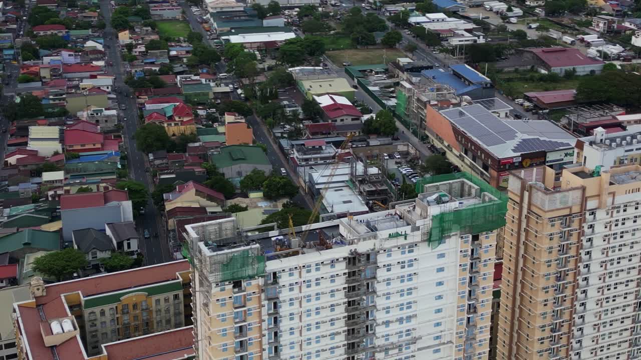 Aerial orbit of crane and construction site atop high-rise condominium rooftop surrounded by residential area at Marikina City, Philippines