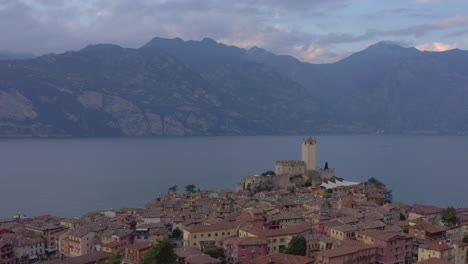 Absteigende-Luftaufnahme-Mit-Blick-Auf-Die-Burg-Scaligero,-Den-Gardasee-Und-Die-Umliegenden-Berge