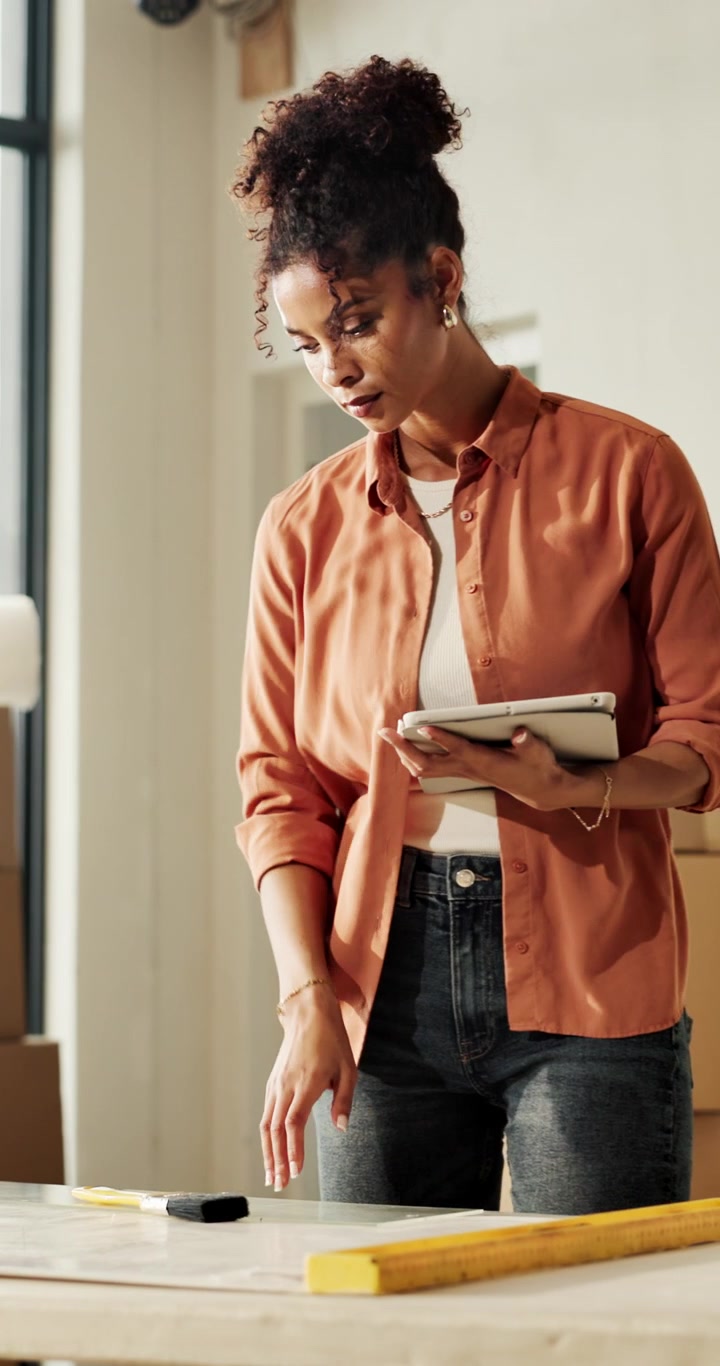 Female Architect Reviewing Blueprints on Tablet in Studio