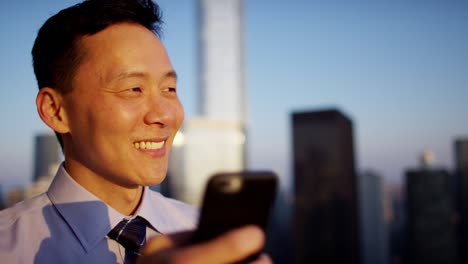 asian businessman using smartphone on rooftop at sunrise