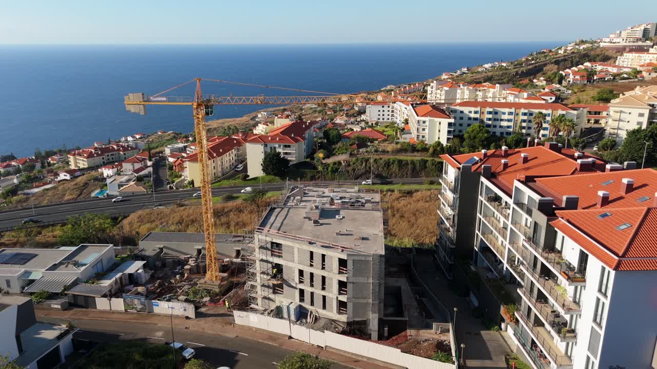 Construction crane and unfinished building near ocean in Funchal, Madeira