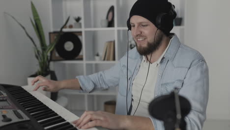 Youn-Excited-Man-Musician-Singing-And-Playing-Electric-Keyboard-At-Home