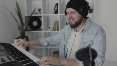 youn emocionado hombre músico cantando y tocando teclado eléctrico en casa