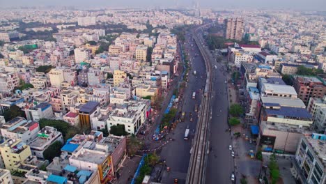 hyderabad metro train with mumbai highway and residential buildings, day time, push in, tilt up, drone shot, 4k.