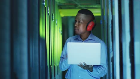 African-american-male-computer-technician-using-laptop-working-in-business-server-room