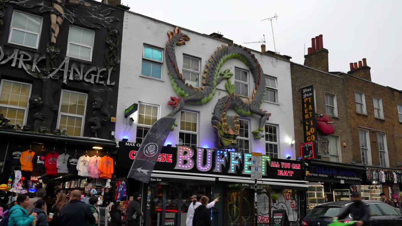 Colorful Camden storefronts in London with dragon and angel decor amid busy street market scene