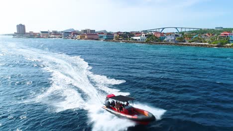 super rib inflatable boat drives quickly along coast of willemstad curacao, aerial tracking follow