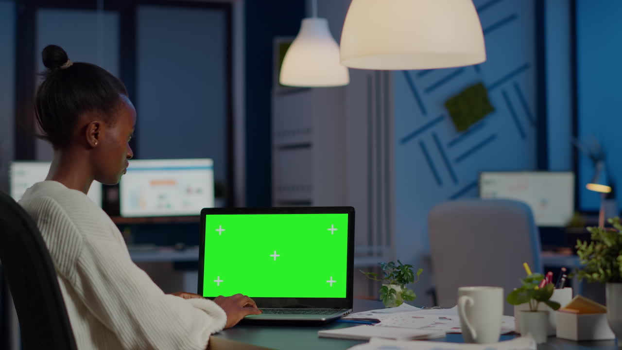 Afrikansk leder taster på bærbar computer med chroma key-skærm under overarbejde