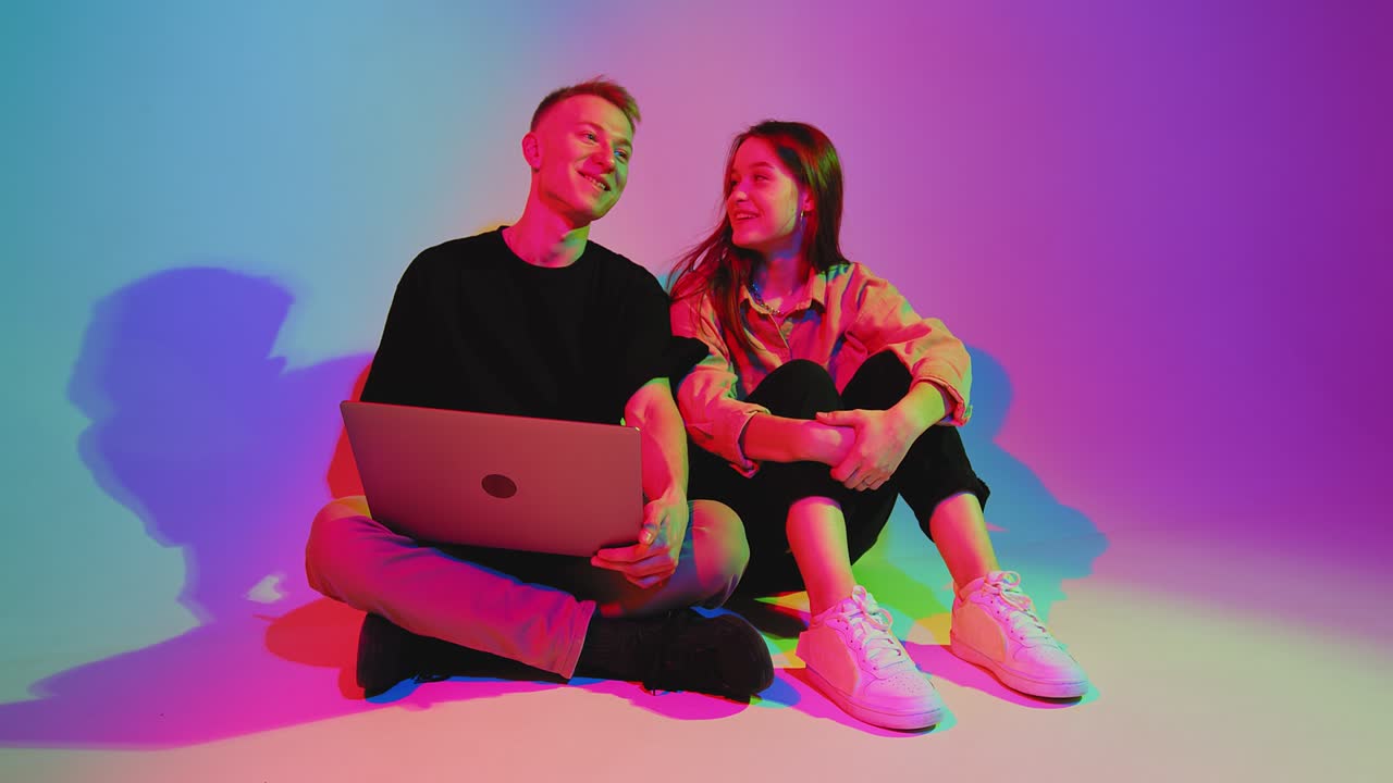 una joven pareja adolescente moderna con una computadora portátil, jugando en la computadora, navegando por las redes sociales, comprando en línea.