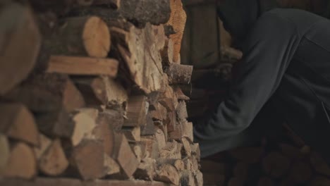 medium wide shot of a man collecting firewood in an old shed