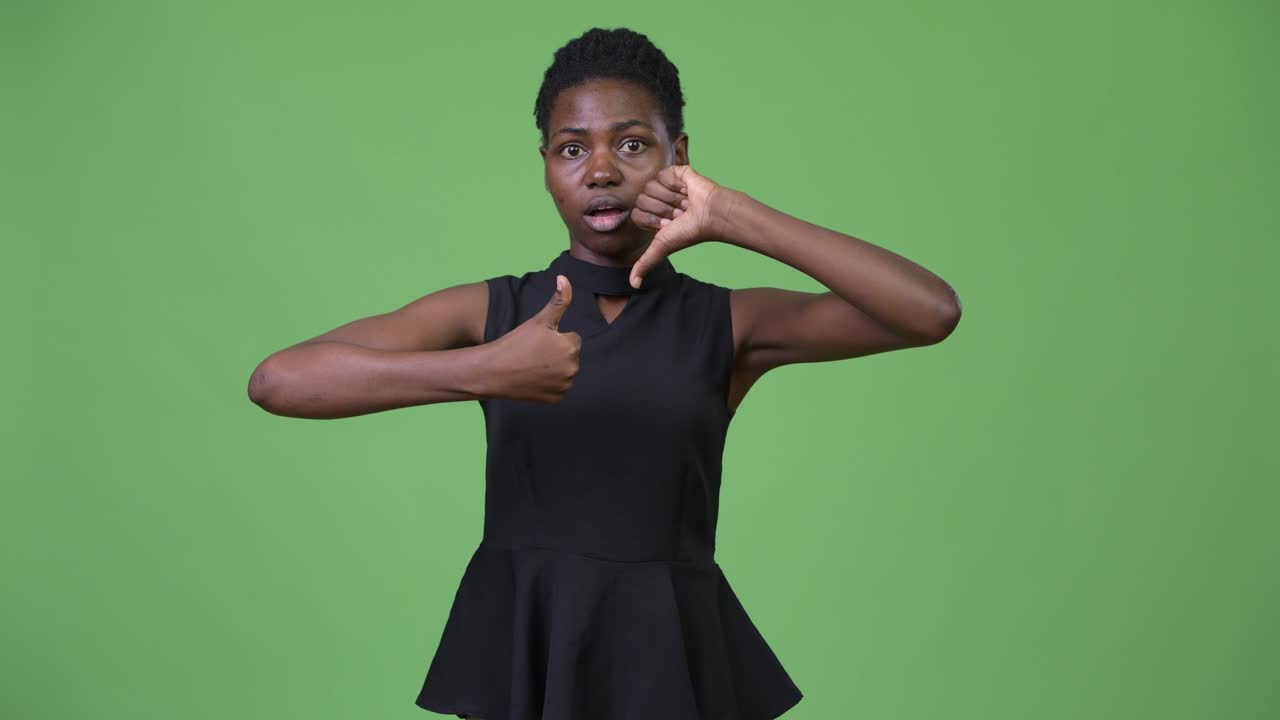 Young beautiful African businesswoman choosing between thumbs up and thumbs down