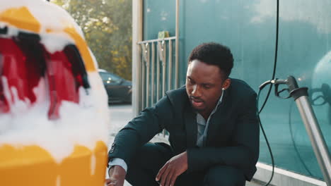 man washing a yellow car at a self-service car wash