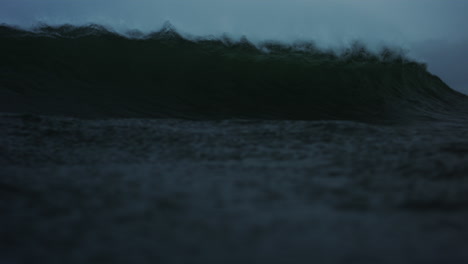 front low view of lip of ocean wave crashing onto surface exploding in whitewash forming barrel tube, view of interior