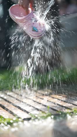 washing a pink child's clogs in the garden