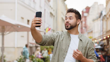 Junger-Blogger,-Der-Ein-Selfie-Per-Smartphone-Videoanruf-Online-Mit-Abonnenten-In-Der-Stadtstraße-Macht