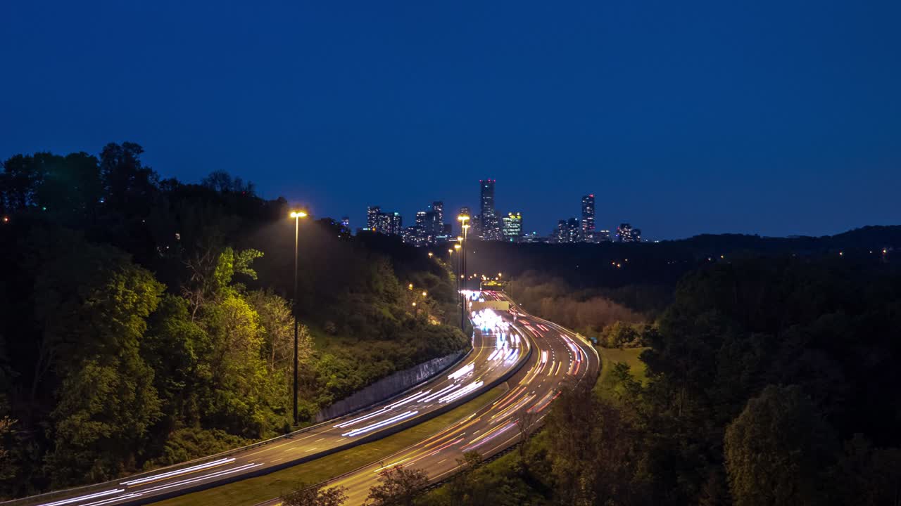 타임스 (timelapse) - 길게 노출된 빛의 흔적과 길을 가로지르는 구부러진 고속도로 도로에서 밤에 토론토 시내의 스카이라인을 향해 가는 트래픽.