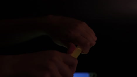 hands activating a yellow glow stick