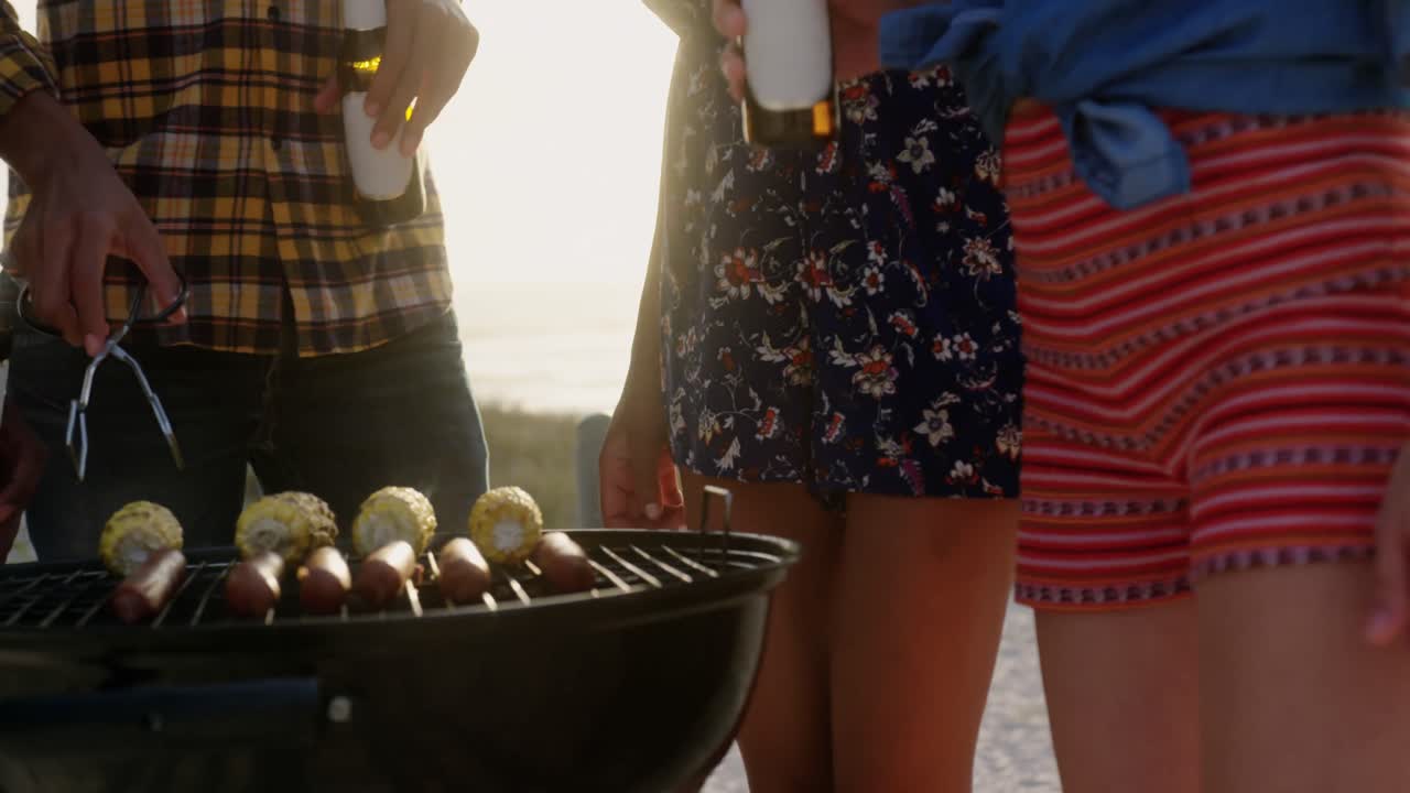 amigos cocinando comida en la barbacoa en la playa 4k