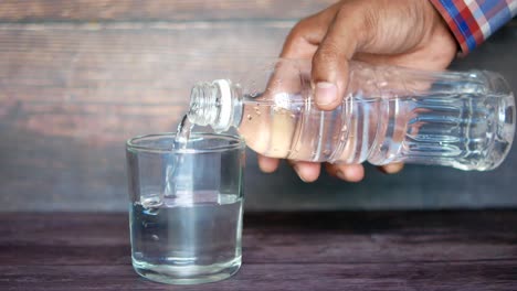 vertiendo agua de una botella en un vaso