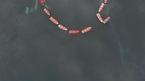 aerial vertical revealing shot from drone over aligned boats in braies lake in the dolomites, italy